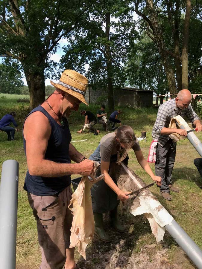 Menschen gerben Felle im Freien.