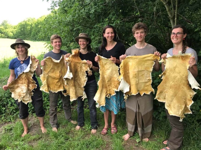 Gruppe präsentiert gegerbte Tierhäute im Freien.
