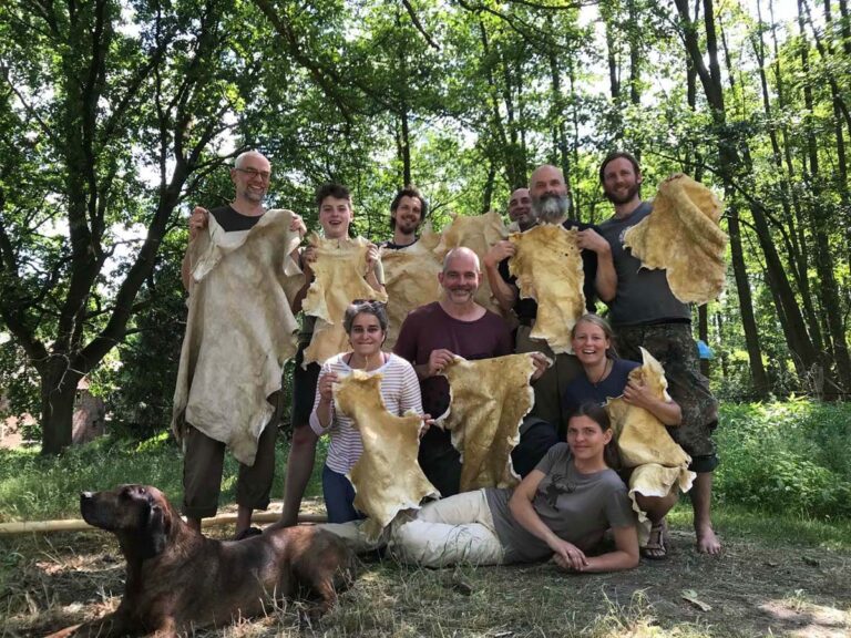 Gruppe mit gegerbten Tierhäuten im Wald