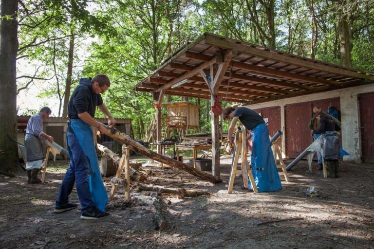 Menschen arbeiten an Holz im Freien.