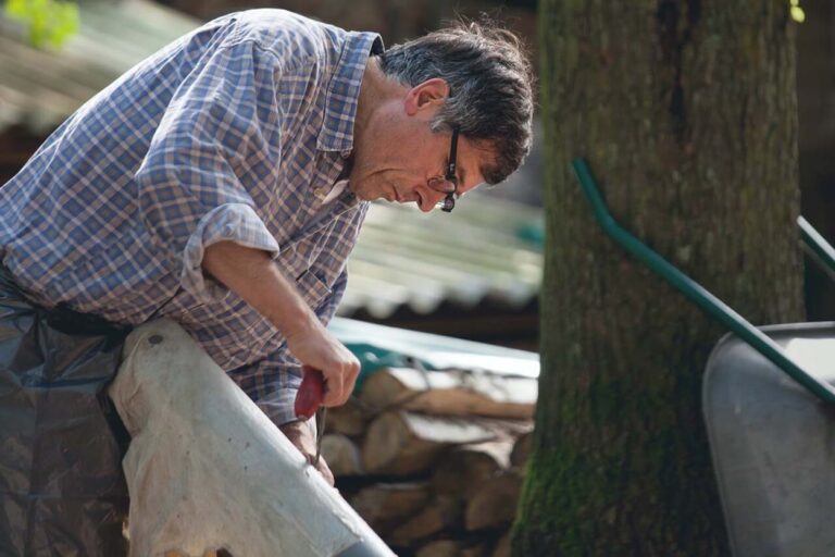 Mann arbeitet mit Werkzeug an Holz