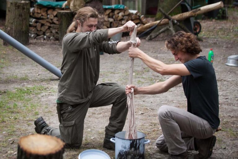 Zwei Personen pressen Stoff im Freien.