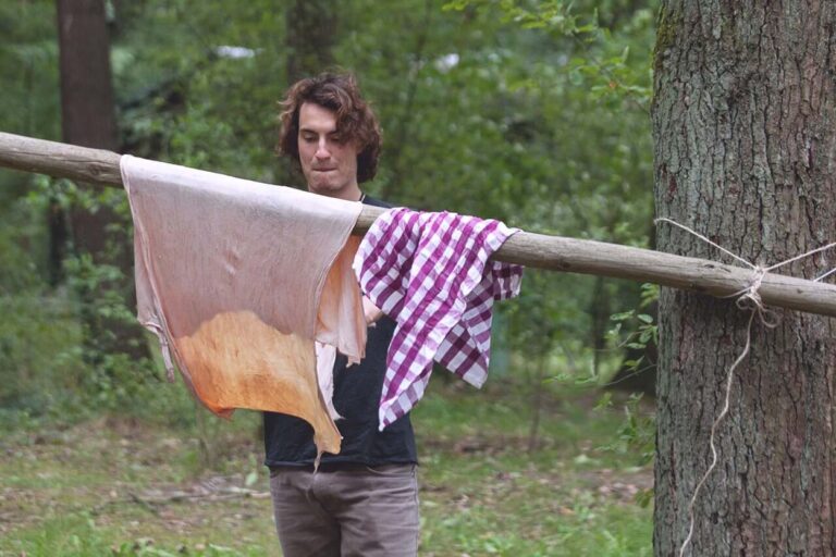 Person hängt Kleidung im Wald auf