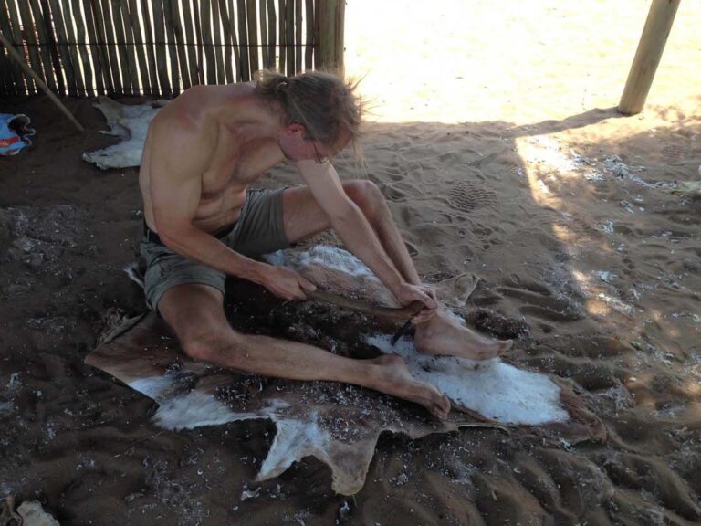 Mann bearbeitet Tierhaut im Freien.