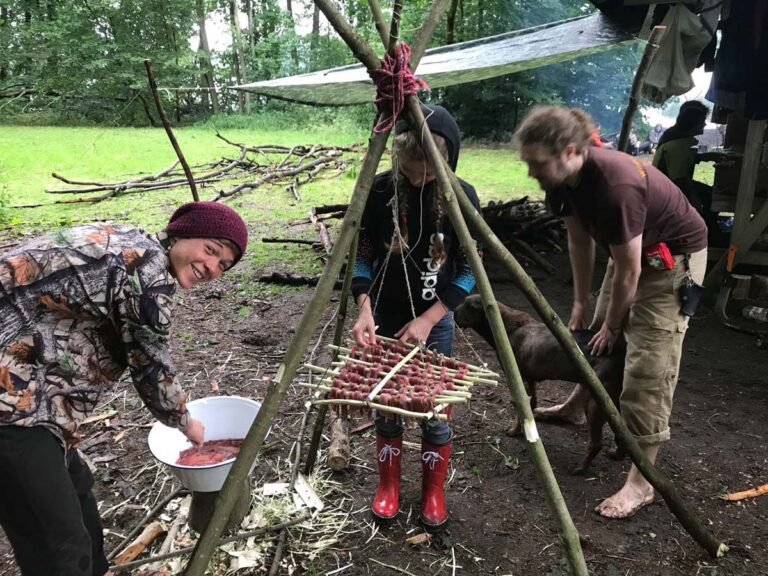 Menschen bereiten Fleisch im Freien zu.