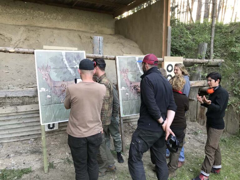 Gruppe analysiert Schießscheibe im Freien.