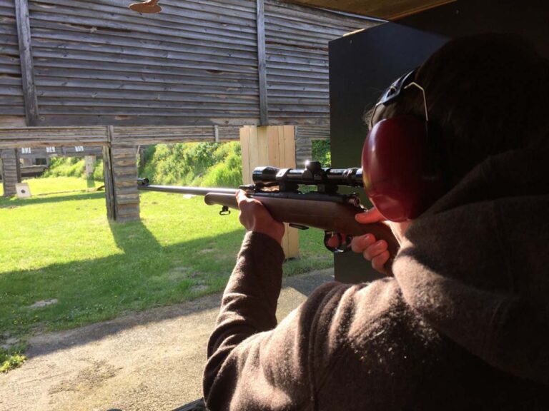 Person schießt auf einem Schießstand mit Gewehr.