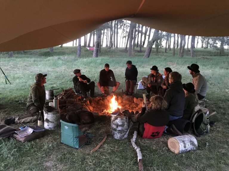 Menschen am Lagerfeuer im Wald sitzend.