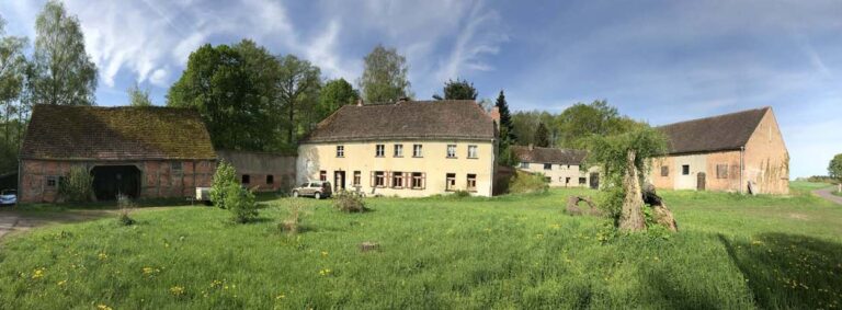 Altes Bauernhaus mit Nebengebäuden im Grünen.