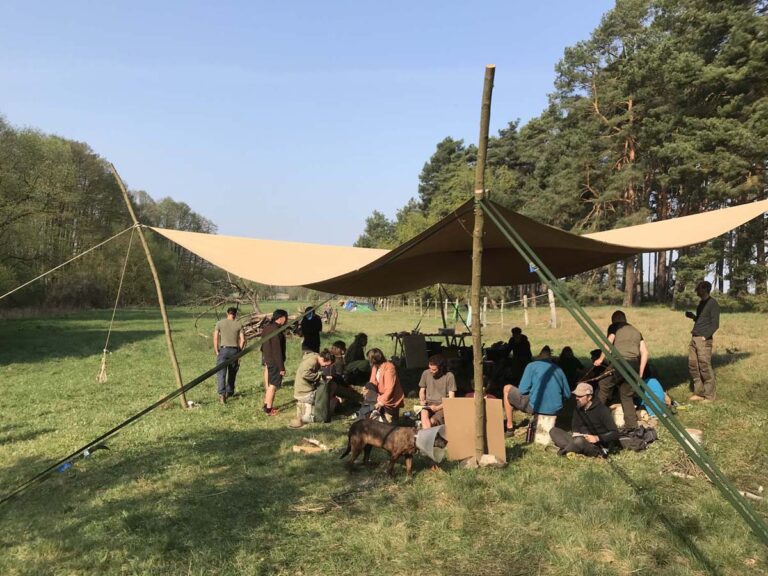 Gruppe unter Zelt im Waldcamp
