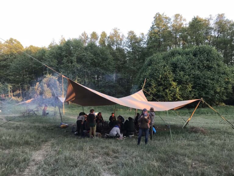 Menschen unter Plane im Wald versammelt.