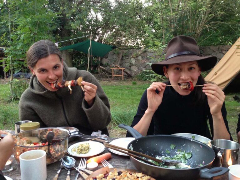 Zwei Personen essen Grillspieße im Freien.