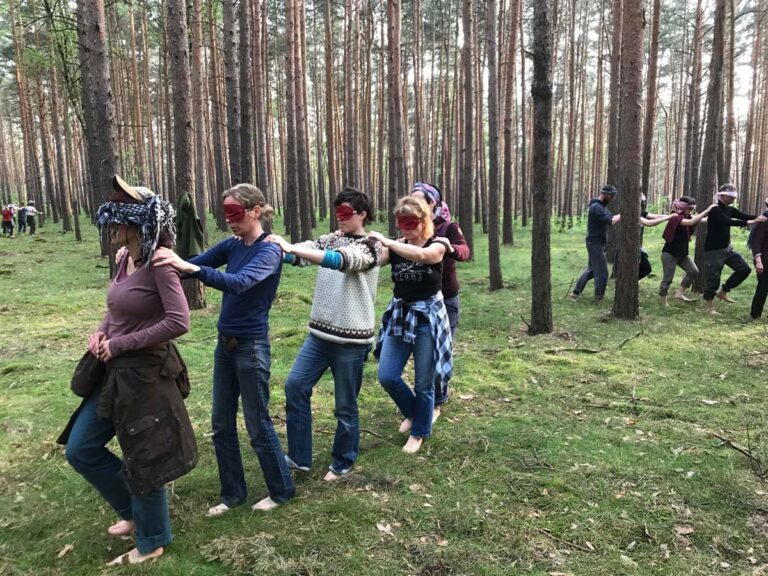 Menschen mit Augenbinden wandern durch den Wald.