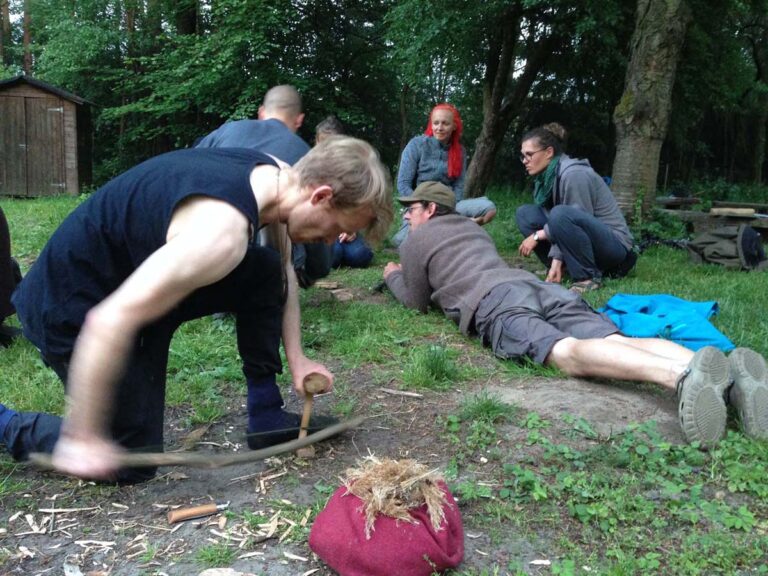 Gruppe übt Feuer machen in der Natur.