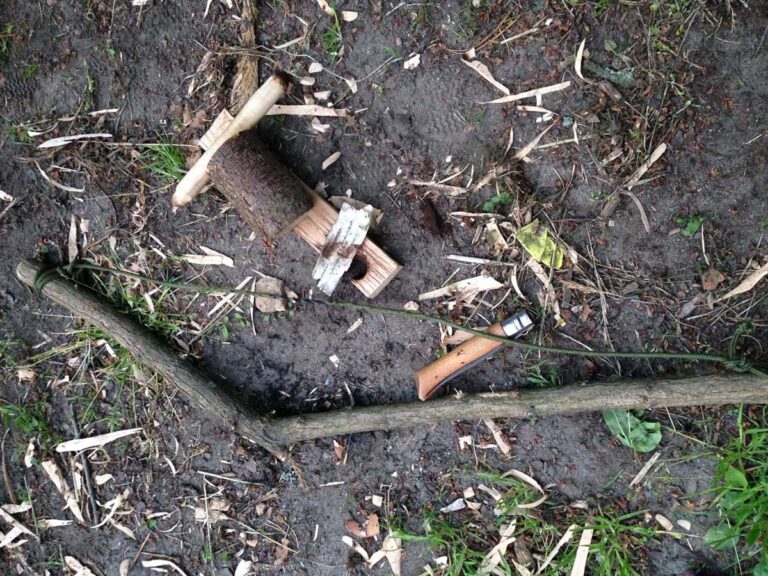 Selbstgebauter Holzbogen und Werkzeuge auf dem Boden