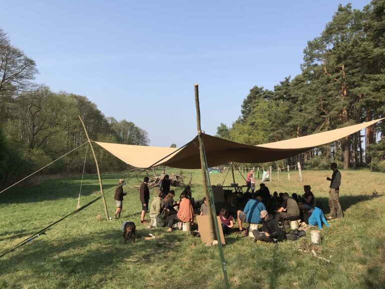 Gruppe Menschen unter Zeltdach im Freien.