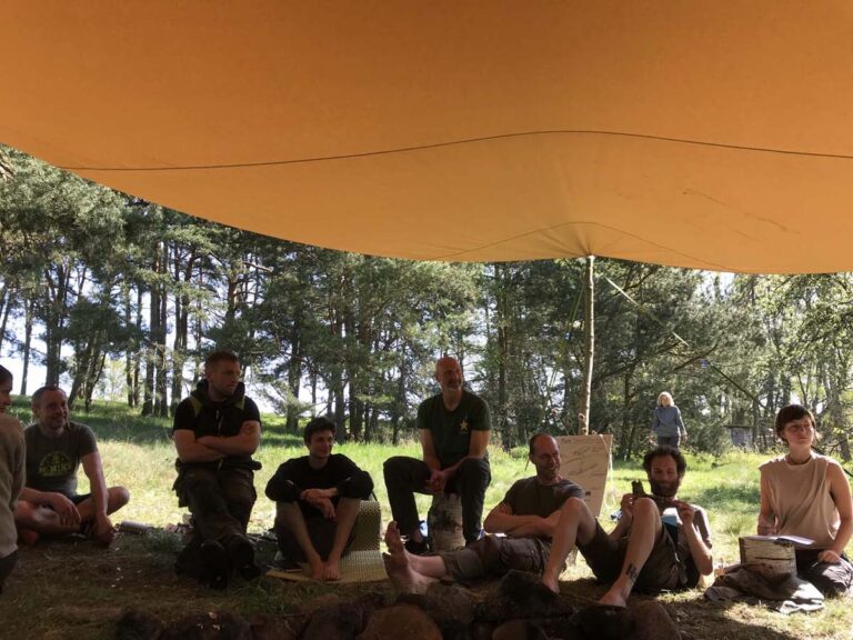 Gruppe entspannter Menschen unter einer großen Plane.