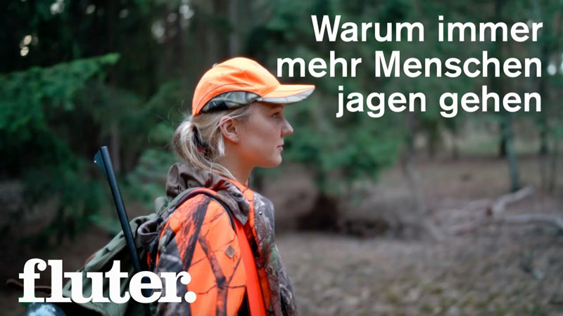 Frau beim Jagen im Wald mit oranger Kleidung.