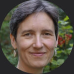 Porträt einer lächelnden Person mit kurzen Haaren.