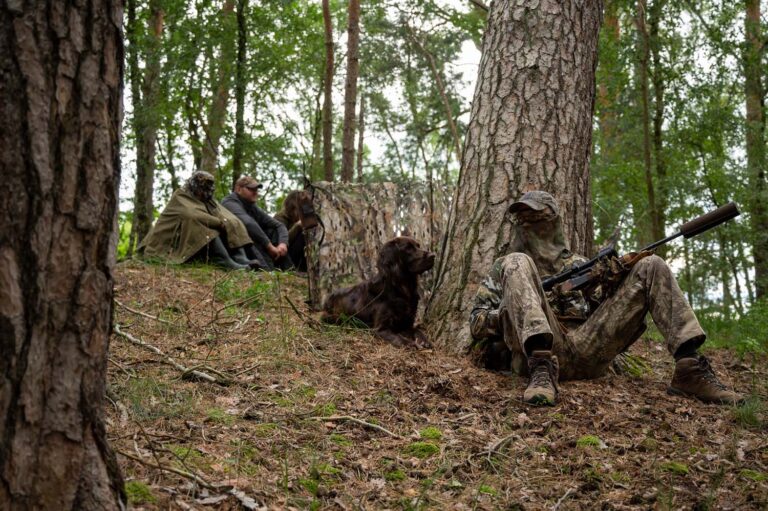 Jäger mit Gewehr und Hund im Wald.