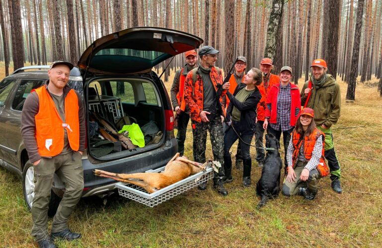 Jägergruppe mit Reh und Hund im Wald