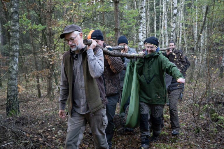 Männer tragen improvisierte Trage im Wald.