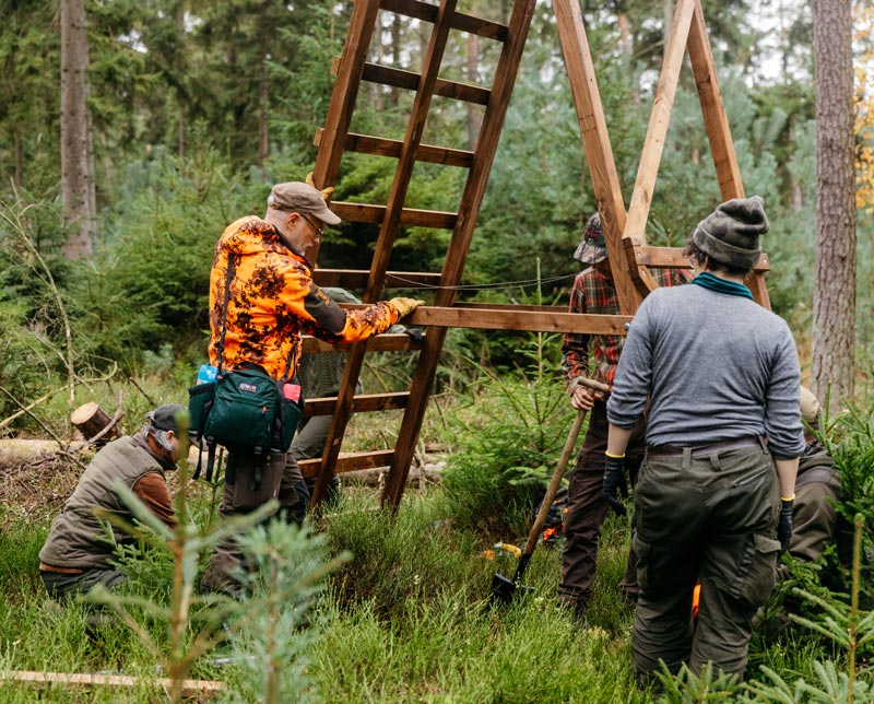 Personen bauen Hochsitz im Wald
