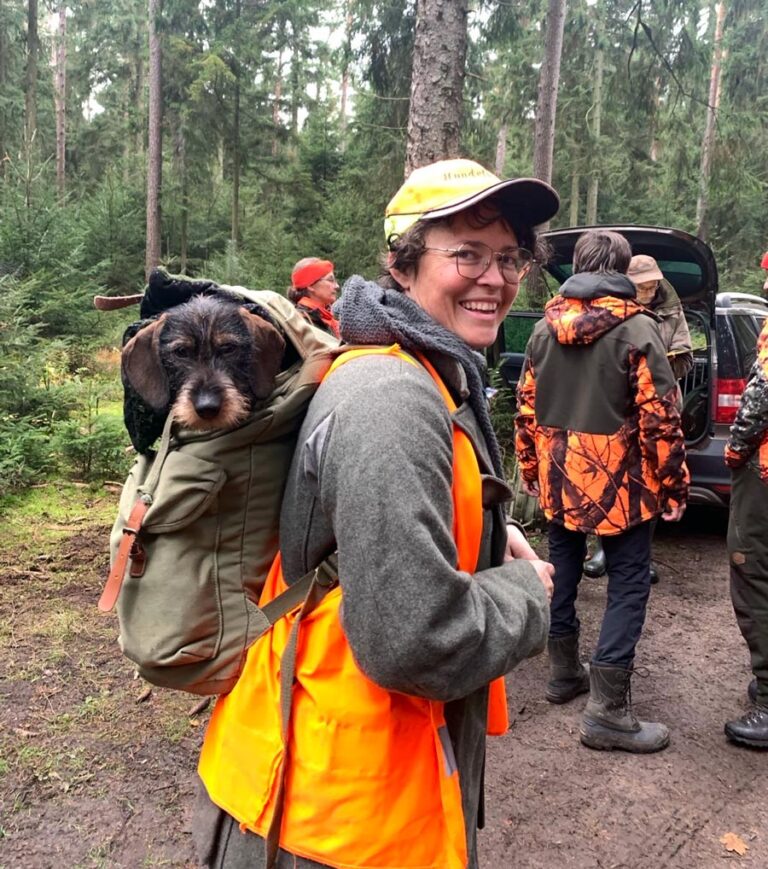 Person mit Hund im Rucksack im Wald