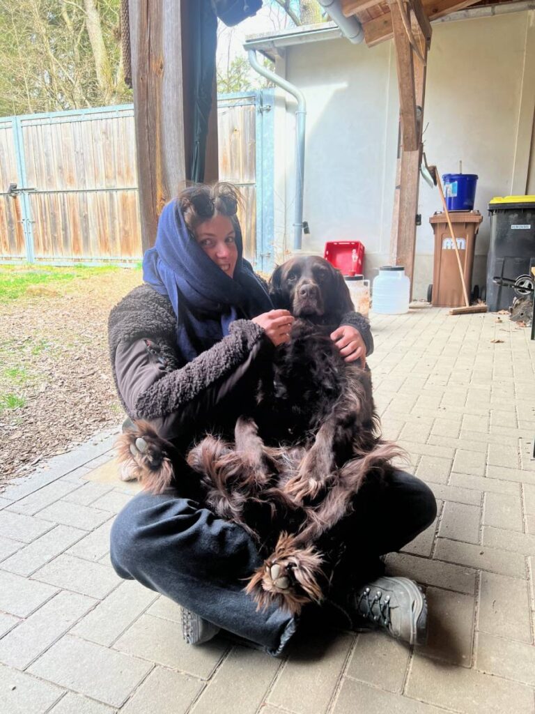 Person mit Hund im Innenhof sitzend