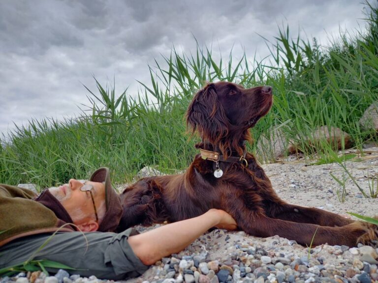 Mann entspannt am Strand mit Hund.