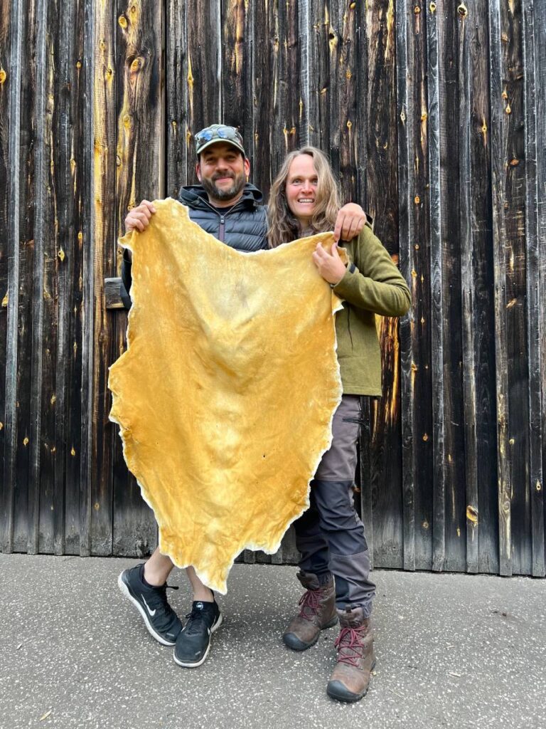 Ein Mann und eine Frau halten ein Damwildleder vor sich