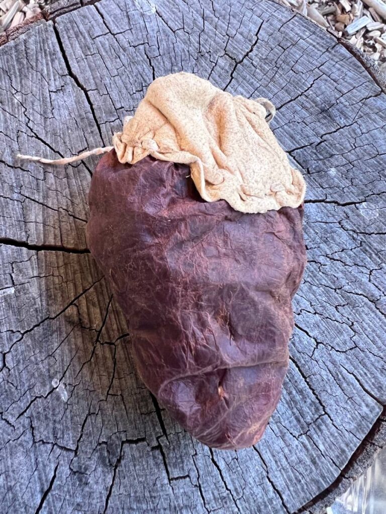 Eingewickelter Gegenstand auf gesägtem Holzstumpf.