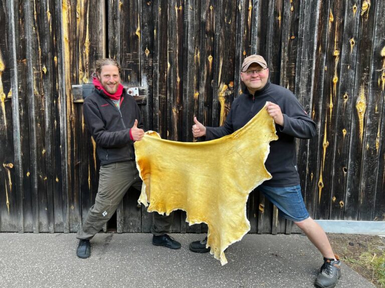 Zwei fröhliche Männer halten ein Leder zwischen sich hoch