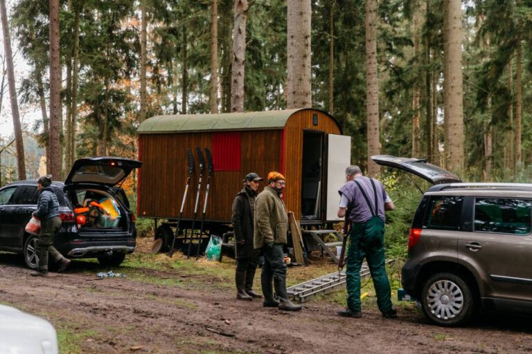 Menschen bei Waldarbeit mit Autos und Anhänger.