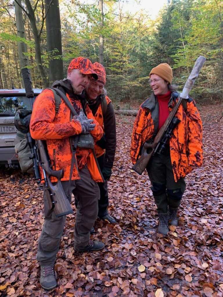 Drei Jäger im Herbstwald in orange Kleidung.