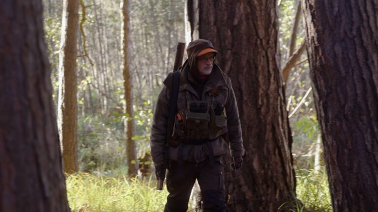 Jäger im Wald mit Gewehr unterwegs