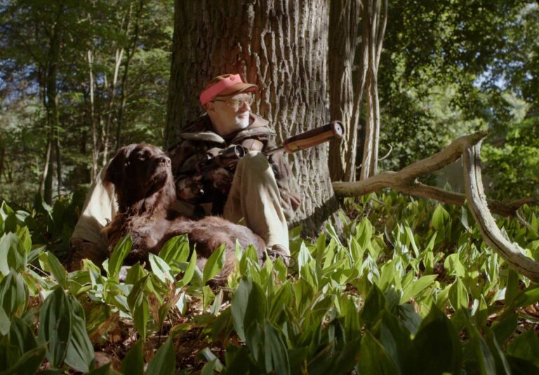 Mann mit Hund im Wald mit Blasrohr