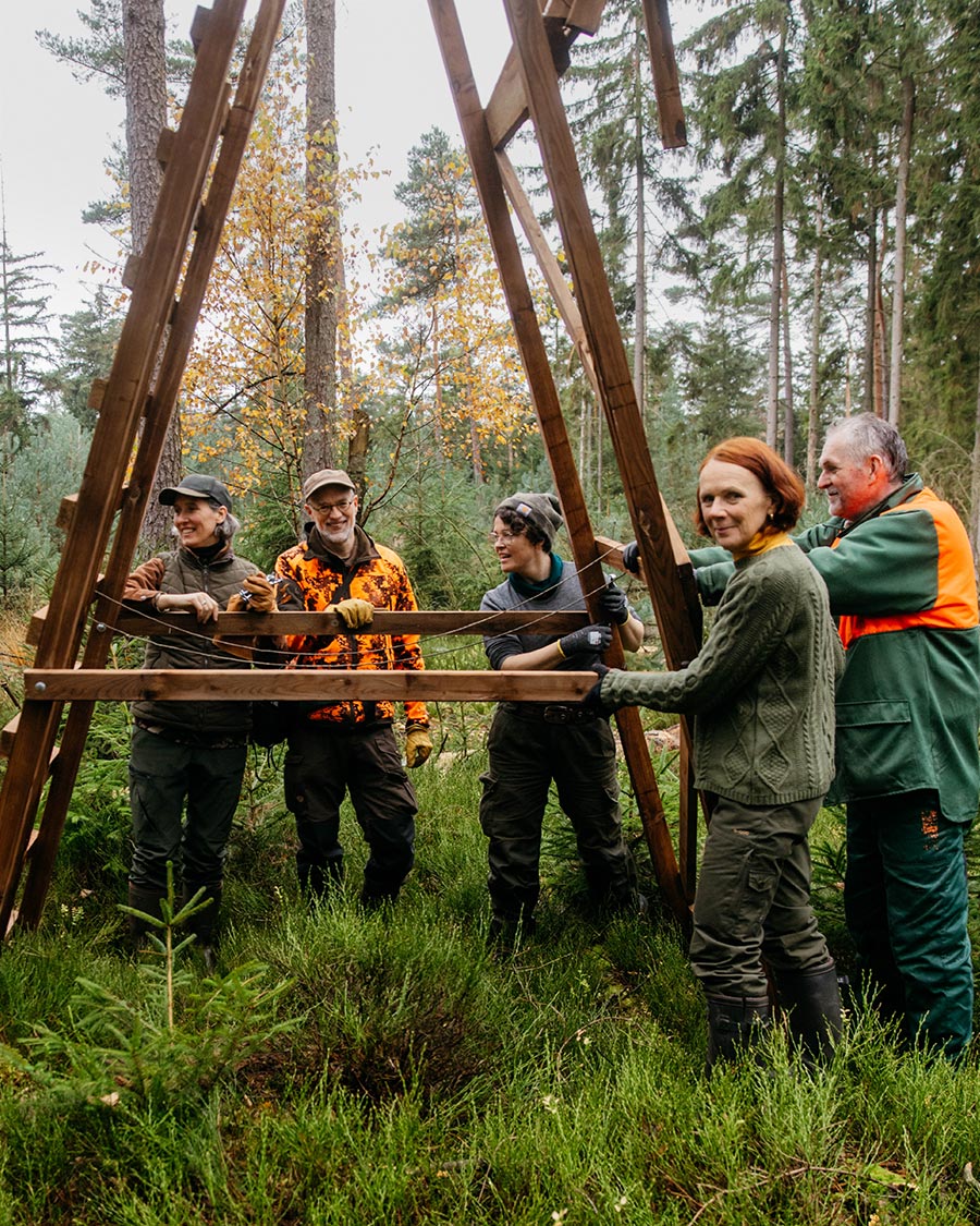 Menschen bauen im Wald eine Holzstruktur.