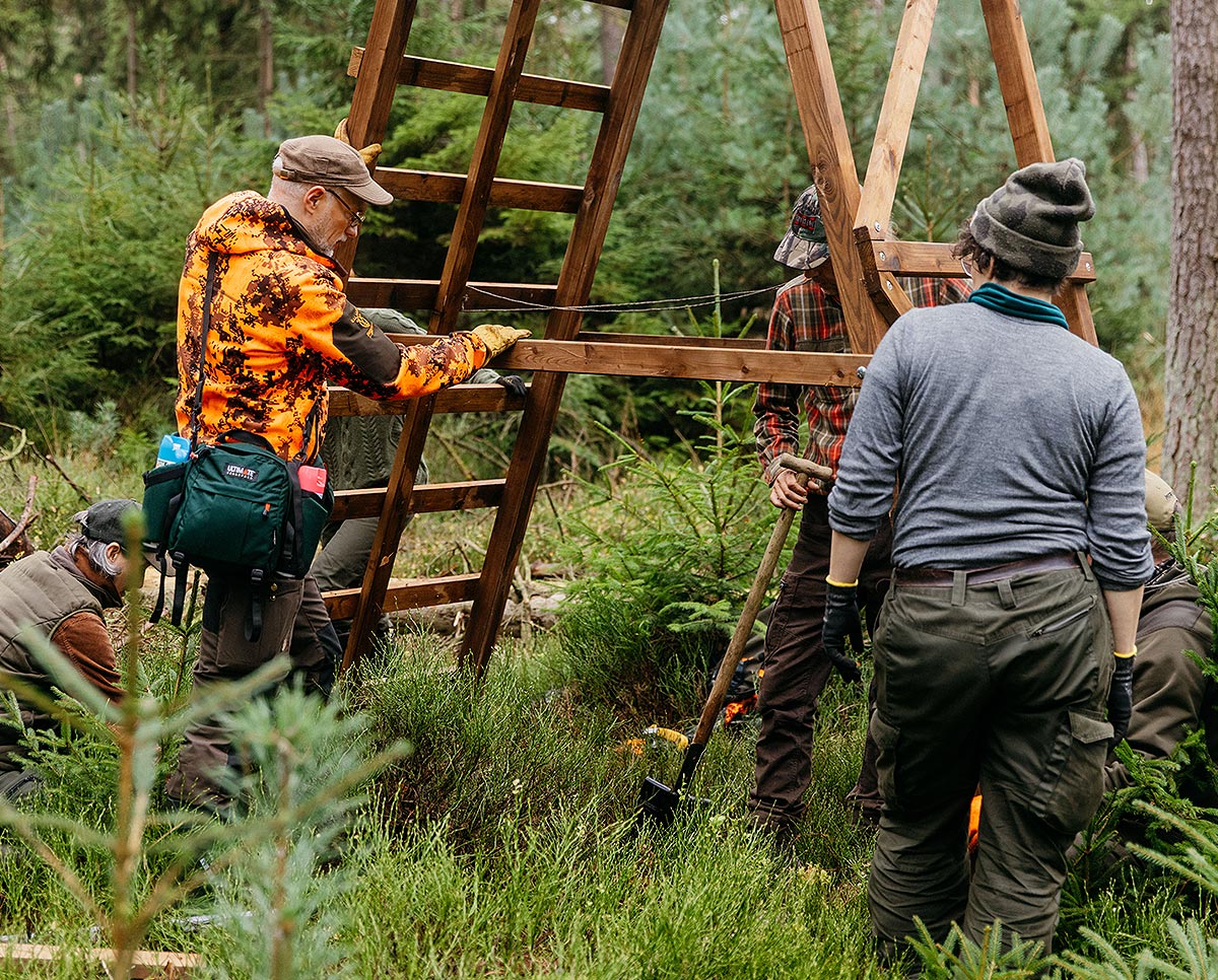 Menschen bauen Hochsitz im Wald zusammen.