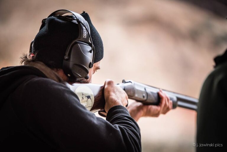 Person zielt mit Gewehr und Gehörschutz.