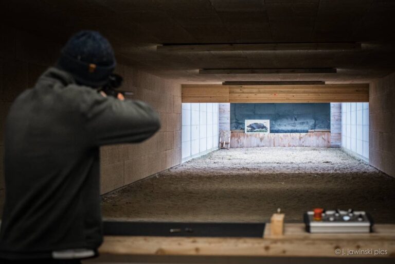 Mann zielt auf Zielscheibe im Schießstand.