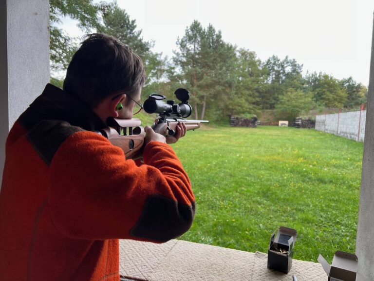 Person zielt mit Gewehr auf grünes Feld