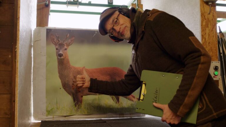 Mann zeigt auf Rehbild im Indoorbereich