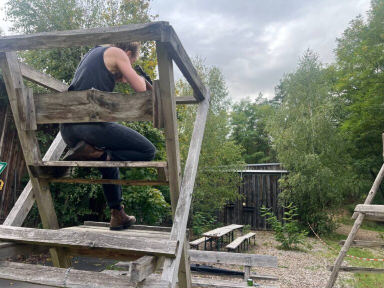 Person sitzt auf Holzgerüst im Freien.