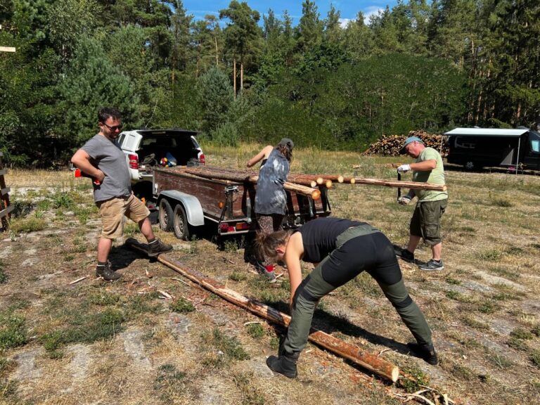 Menschen laden Holz im Freien ab.