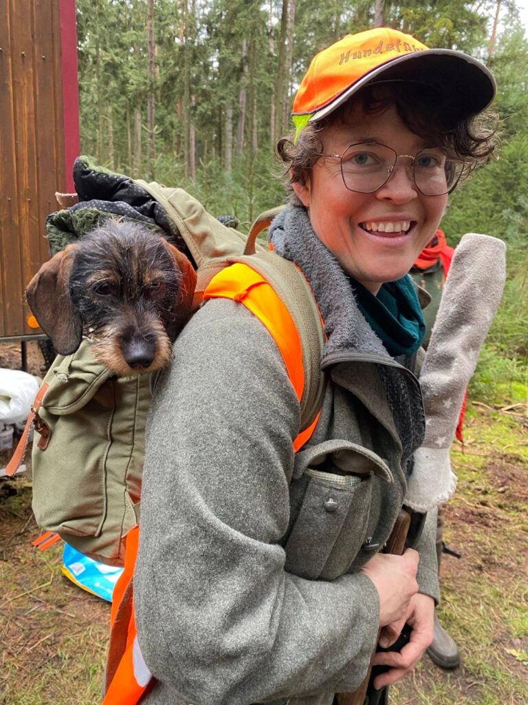 Frau mit Hund im Rucksack im Wald