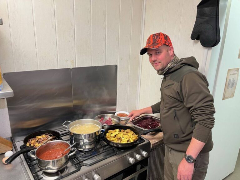 Mann kocht in einer Küche mit mehreren Töpfen.