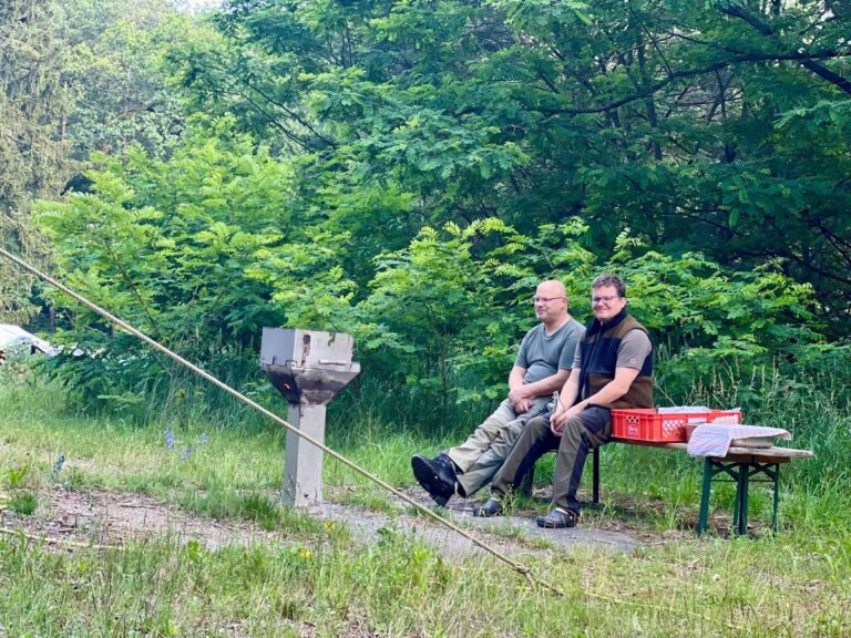 Zwei Menschen sitzen auf einer Bank im Grünen.