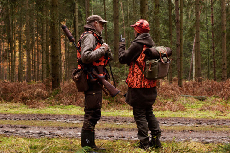 Zwei Jäger im Wald, in orange gekleidet.